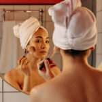 girl-looks-in-mirror-in-bathroom-and-applies-tonal-2023-11-27-05-26-46-utc