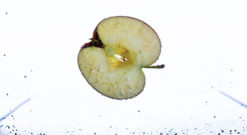 Half of apple floats in aquarium with white background